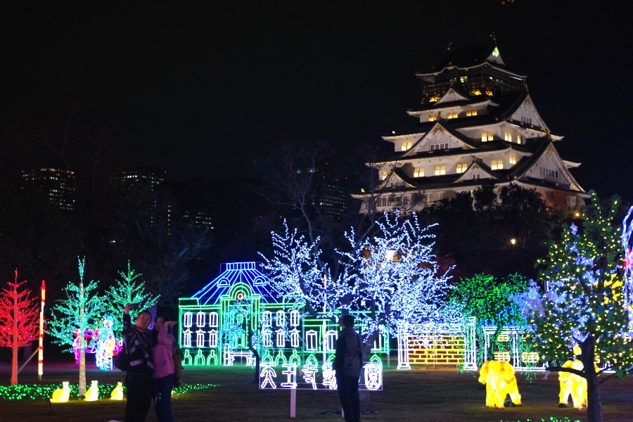大阪城天守閣をバックにカラフルに彩られたイルミネーションを楽しむ人たち（１１月２２日・大阪城西の丸庭園）