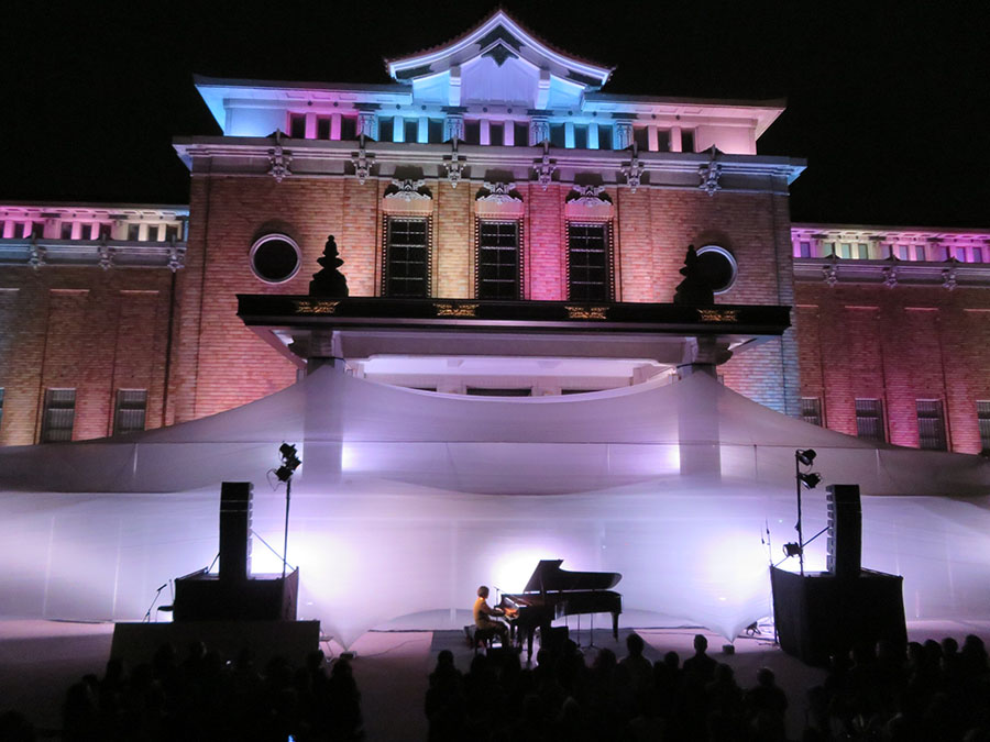 高橋匡太による本館ライトアップをバックに演奏する高木正勝。観客は極上の光と音の競演に酔いしれた