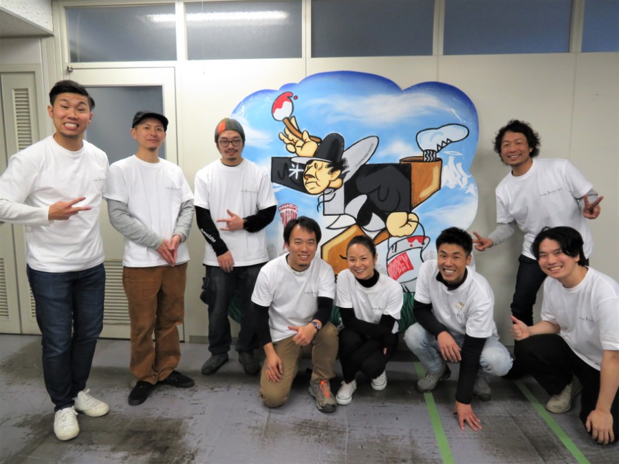 ライブペインティングで完成した絵と神戸ミューラルアートプロジェクト実行委員会のメンバー。左から４番目が代表の秋田大介さん（２月２日・神戸市役所）