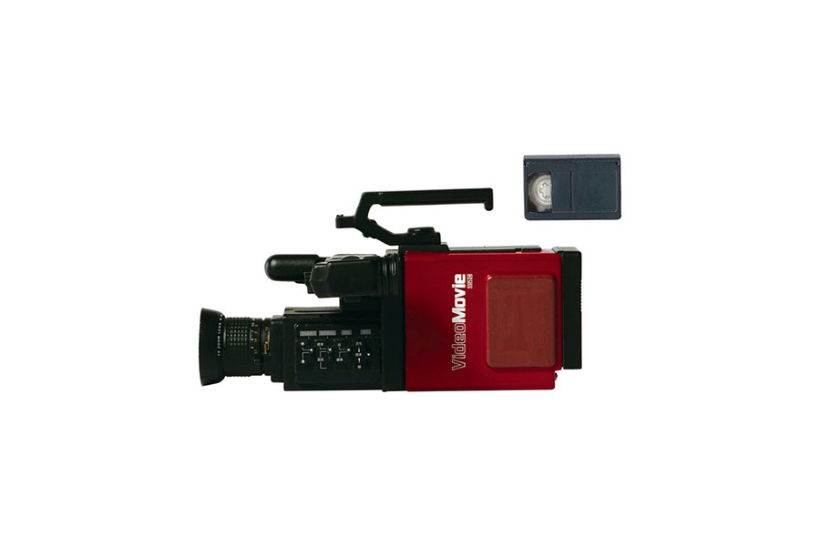 1984年の発売当時、世界最小・最軽量のカメラ一体型ビデオカメラとして様々なシーンで活躍した「ビデオカメラ VideoMovie（GR−C1）＆ ビデオテープ」はバッテリーを本体から取り出せる