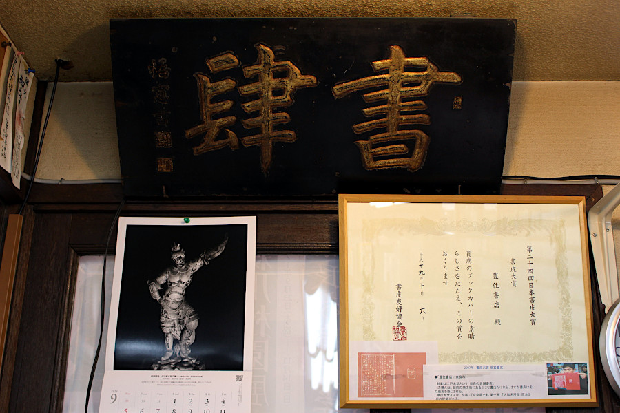 店内レジ裏に掲げられた2007年には「第24回日本書皮大賞」の賞状と歴史を感じる扁額