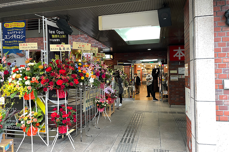 祝福の花がずらりと並ぶ書店前。行き交う人々が興味津々で店に顔を覗かせていた