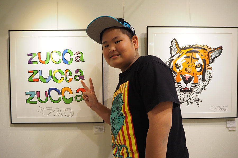 大阪会場を訪れたイラストレーターのミラクルくん(12月18日撮影)。背景には「ZUCCa」とコラボしたデザイン画も