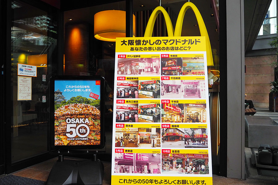 大阪1号店から10号店までの店舗写真が並ぶ特別パネルと大阪出店50周年記念のポスター