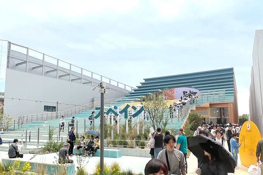 写真右側、黄色の看板の奥へと進む。行列の横を過ぎて建物の奥まで進むべし(4月20日撮影)