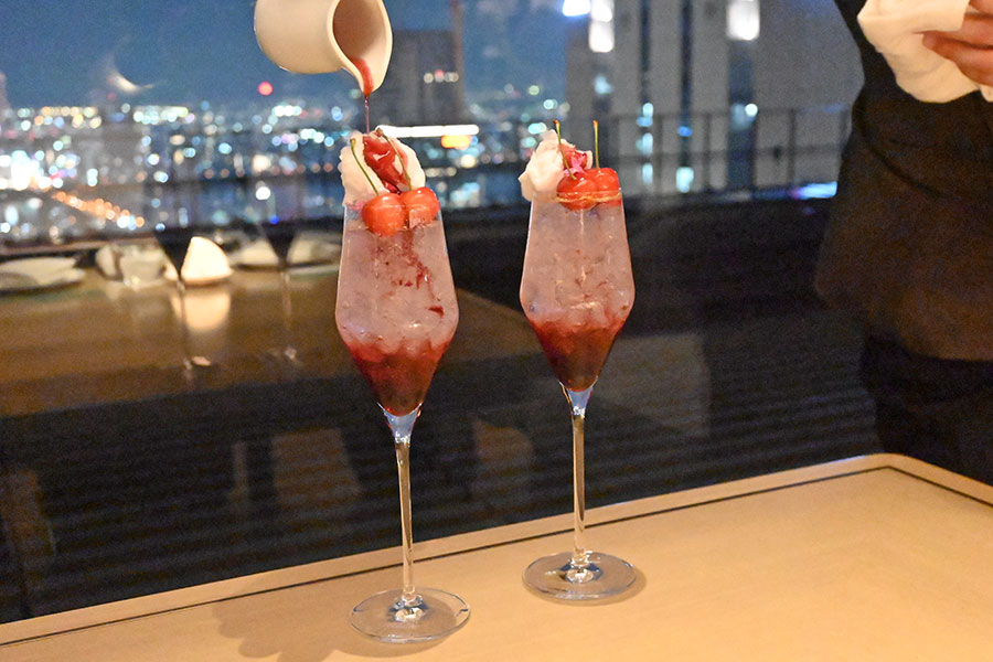 厚なチェリーシロップを、大阪のご当地サイダー「三扇ビリケンサイダー」で割ったウェルカムドリンク「Cherry Wind」は、グラスの上に飾られた綿菓子に、目の前で追いシロップをかけて提供される