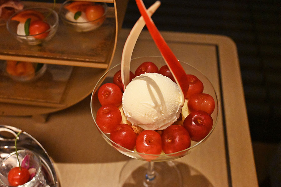 さくらんぼがグラスの縁に並ぶパフェは、さくらんぼとキルシュのジュレ、ピスタチオクリーム、スポンジケーキ、バニラアイスが層になっている