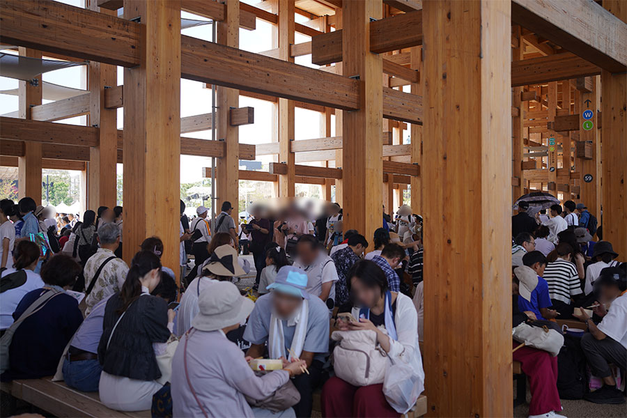 『大阪・関西万博』の大屋根リング下で休憩する人々のようす。知らない人と隣り合って座ることも度々(撮影:Lmaga.jp)。