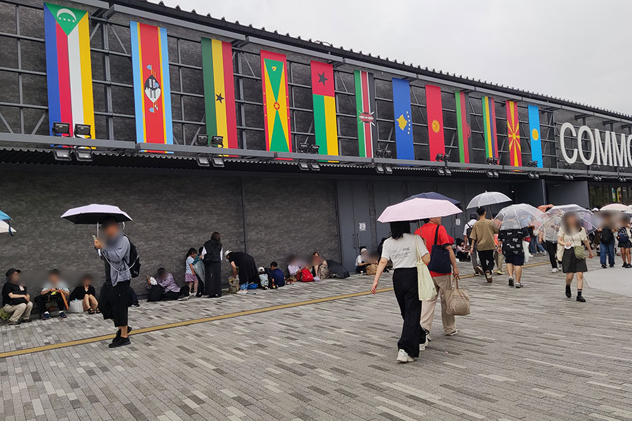 『大阪・関西万博』の「コモンズA館」前で雨宿りをする人びと(6月23日・16時/Lmaga.jp撮影)