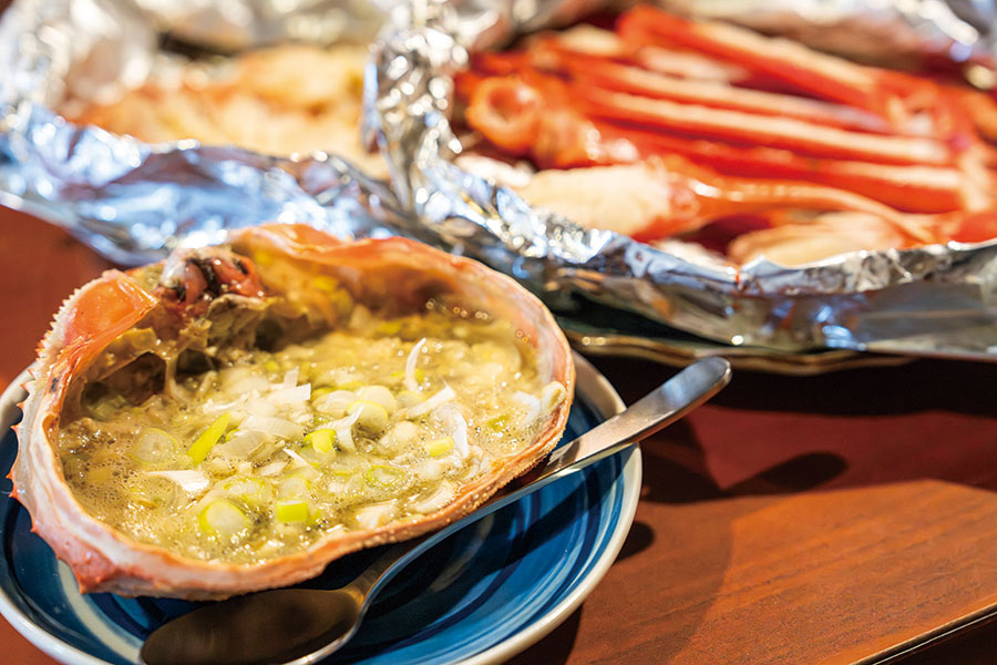 毎朝漁師の船まで直接買い付けに行く、紅ズワイガニ炭火焼4,000円は入荷次第で提供。甲羅に熱燗を注いで飲む人も。