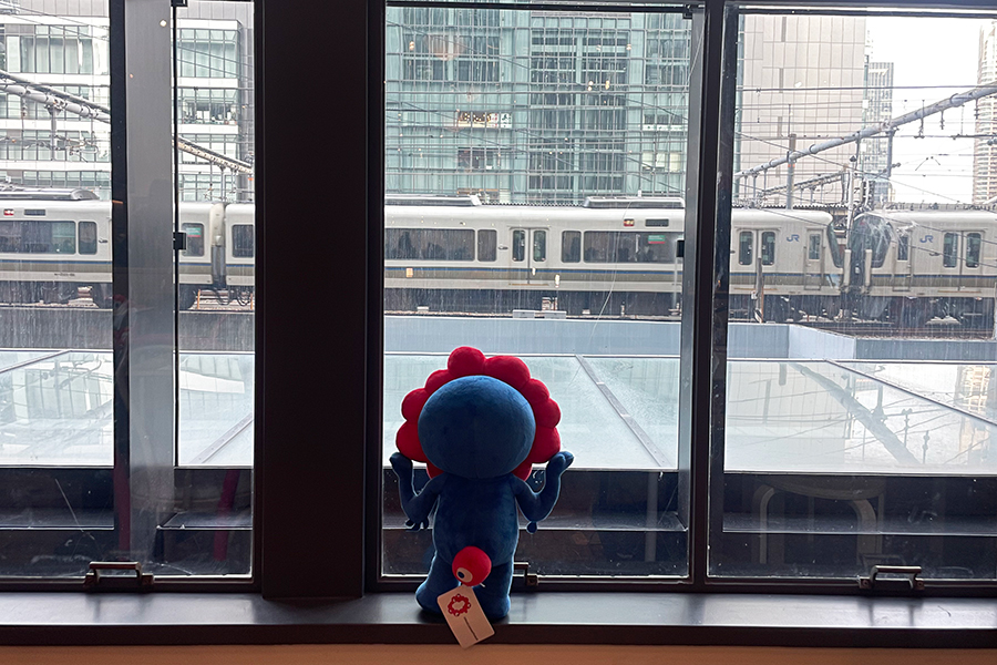 窓からそっと外を見つめるミャクミャク